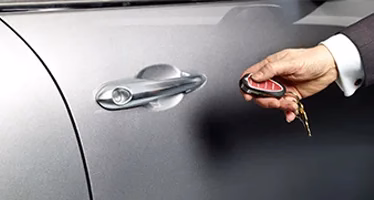 a hand pressing a car key remote button