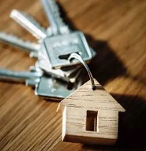 a key ring with a wooden charm of a house